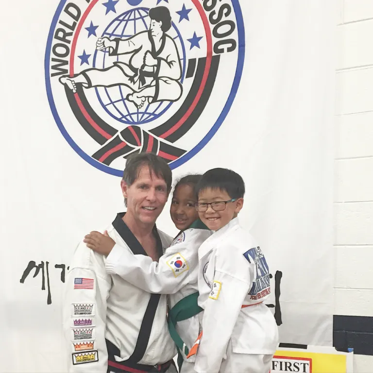 Dr. Tim Schroeder in his Tang Soo Do uniform with two young students after a belt test
